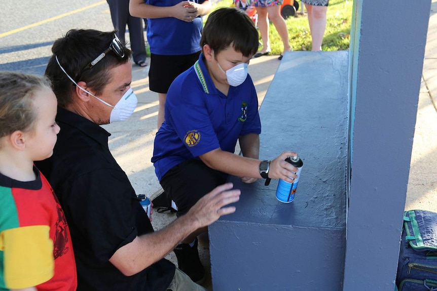 children painting a bus stop with spray paint