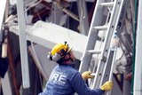 Rescue workers attempt to deliver a bottle of water to a trapped earthquake survivor