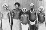 Black-and-white photo shows five Solomon Islander men standing in a line after being recruited to work on plantations.