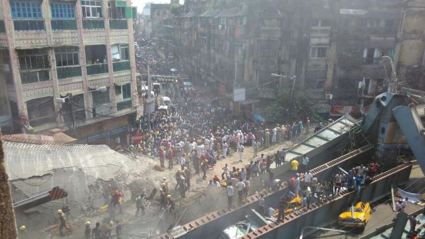 Hundreds of people crowd around debris strewn street as emergency services work to free people trapped under rubble