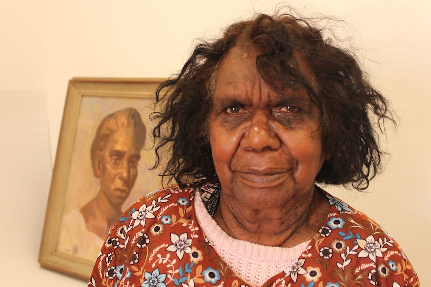 Judith Inkamala stands next to the portrait