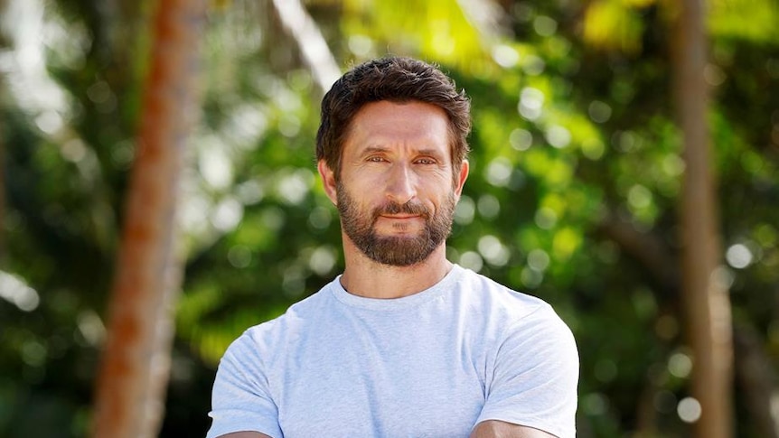 An actor posing for a portrait in front of a jungle