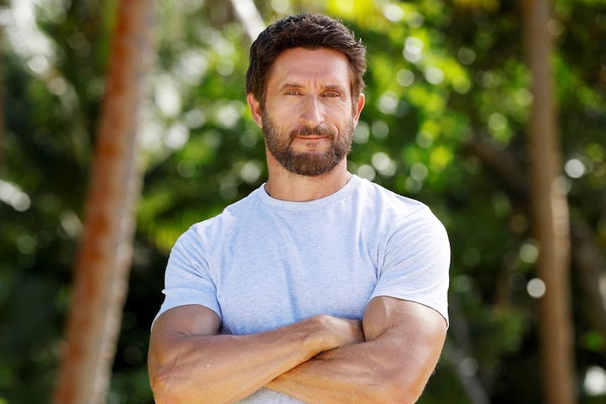 An actor posing for a portrait in front of a jungle