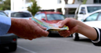 The hand of an older man takes cash from the hand of a young woman.