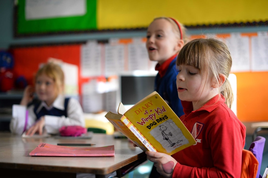A child reads a book in a classroom.