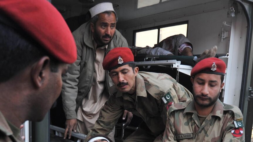 Army soldiers help a man injured by the suicide bombing