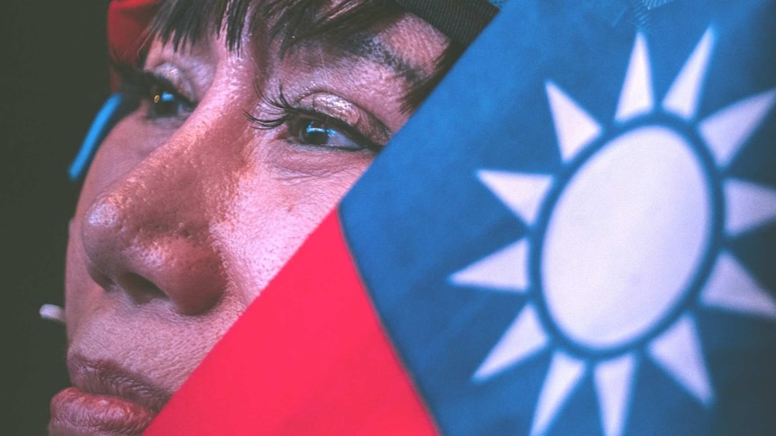 A Taiwanese woman looks upwards, her face partly obscured by her country's flag.