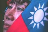 A Taiwanese woman looks upwards, her face partly obscured by her country's flag.