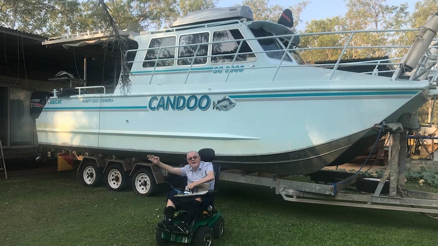 Paralysed man in wheelchair in front of modified fishing boat.