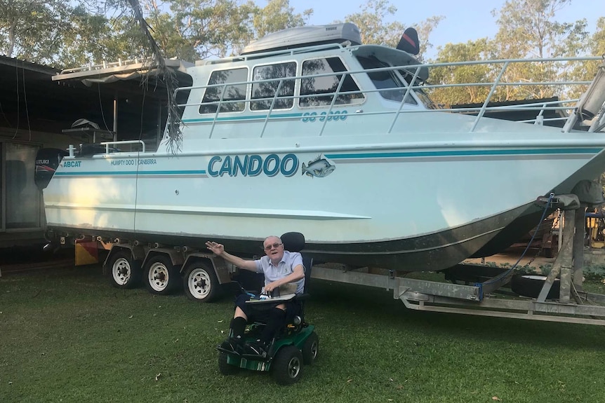 Paralysed man in wheelchair in front of modified fishing boat.