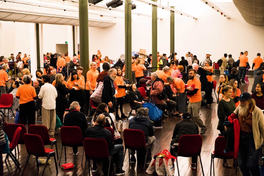 More than a dozen hairdressers cut the hair of attendees at Sydney Homeless Connect, while others wait for their turn.