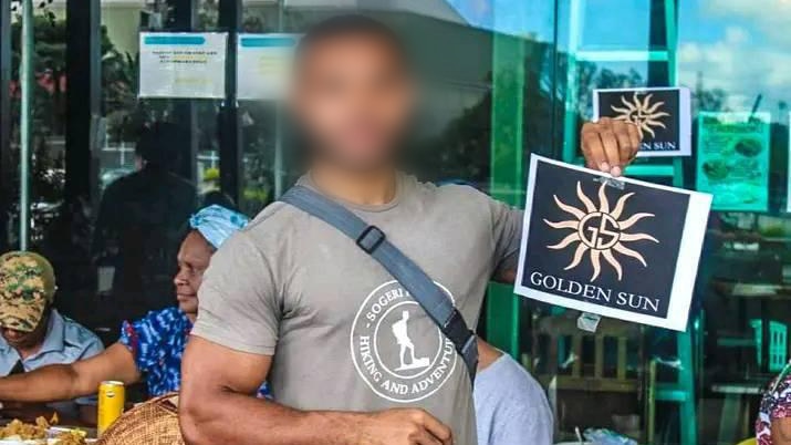 A young Papua New Guinean holds up a sheet of paper printed with the words golden sun