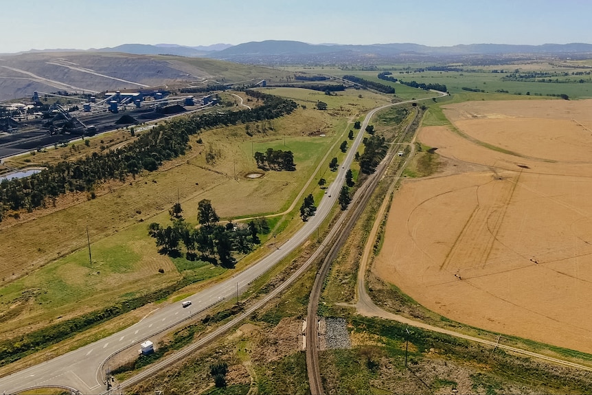 A road running with a coal mine on the left and farmland in the middle