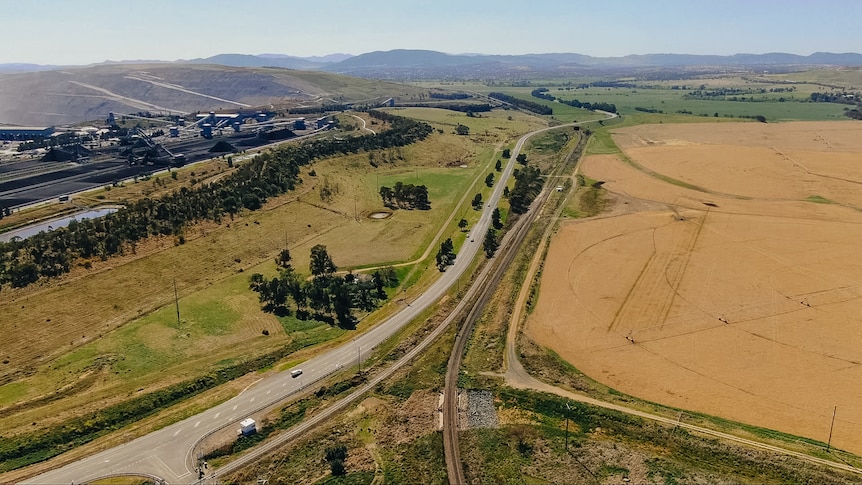 A road running with a coal mine on the left and farmland in the middle.