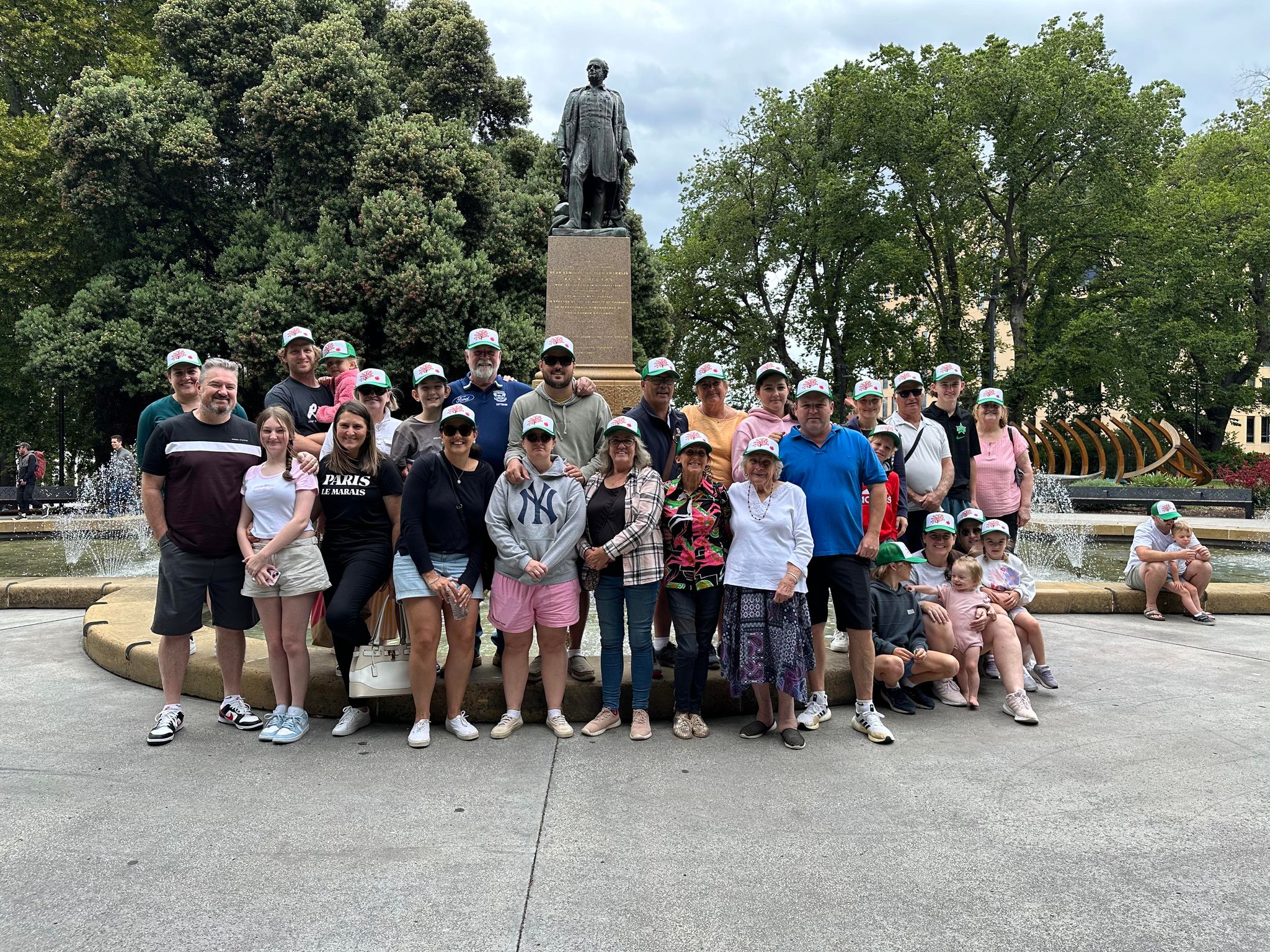 A large family group stands in a town square in front of fountain.