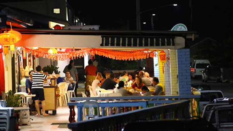 A Chinese restaurant at night filled with people sitting in an outdoor area under a roof.