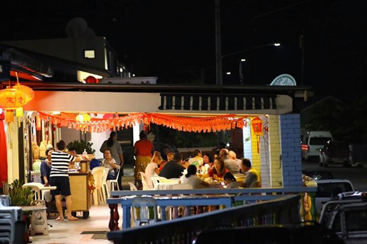 A Chinese restaurant at night filled with people sitting in an outdoor area under a roof.