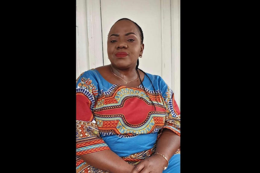 A woman smiles at the camera wearing a colourful shirt