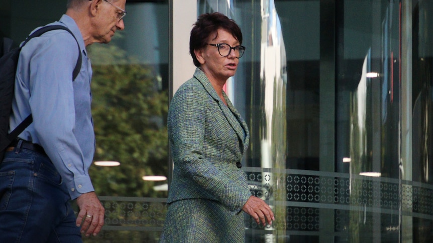 A woman wearing a green suit leaves the courthouse.
