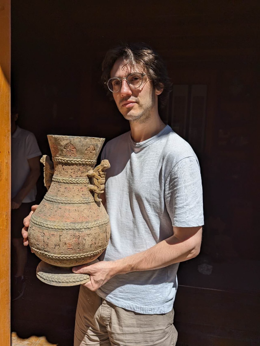 A man holding an antique vase