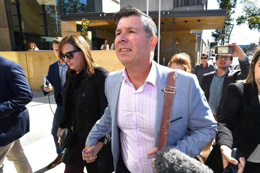 Former Ipswich Mayor Andrew Antoniolli and his wife leave the Ipswich Magistrates Court surrounded by media in 2019.