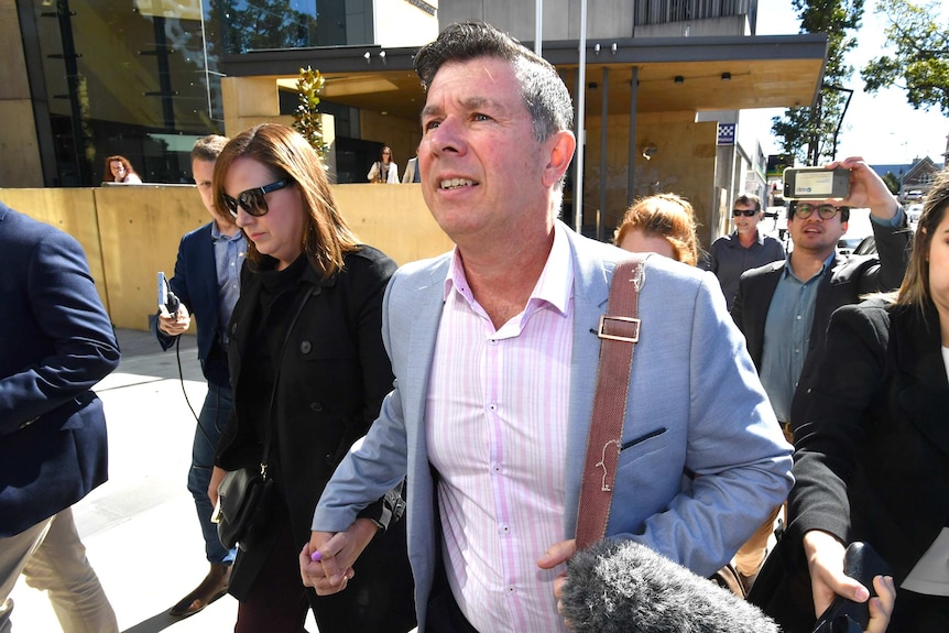 Former Ipswich Mayor Andrew Antoniolli and his wife leave the Ipswich Magistrates Court surrounded by media.