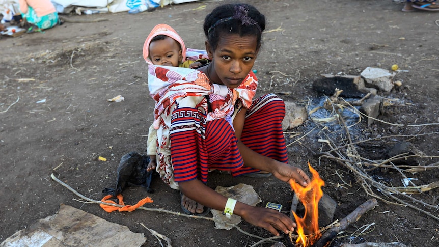 An Ethiopian woman, who fled the ongoing fighting in Tigray region, carries a child on her back