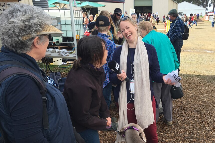 A person with a microphone interviews a woman with a dog. 