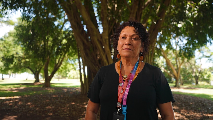 Woman stands in front of tree with lanyard around neck 