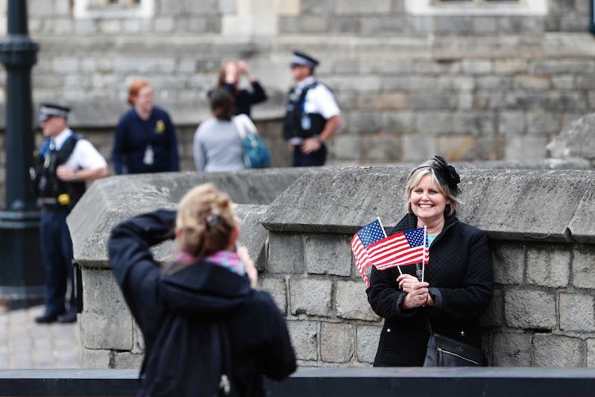 Diane Calderon holds two US flags outside windsor castle.