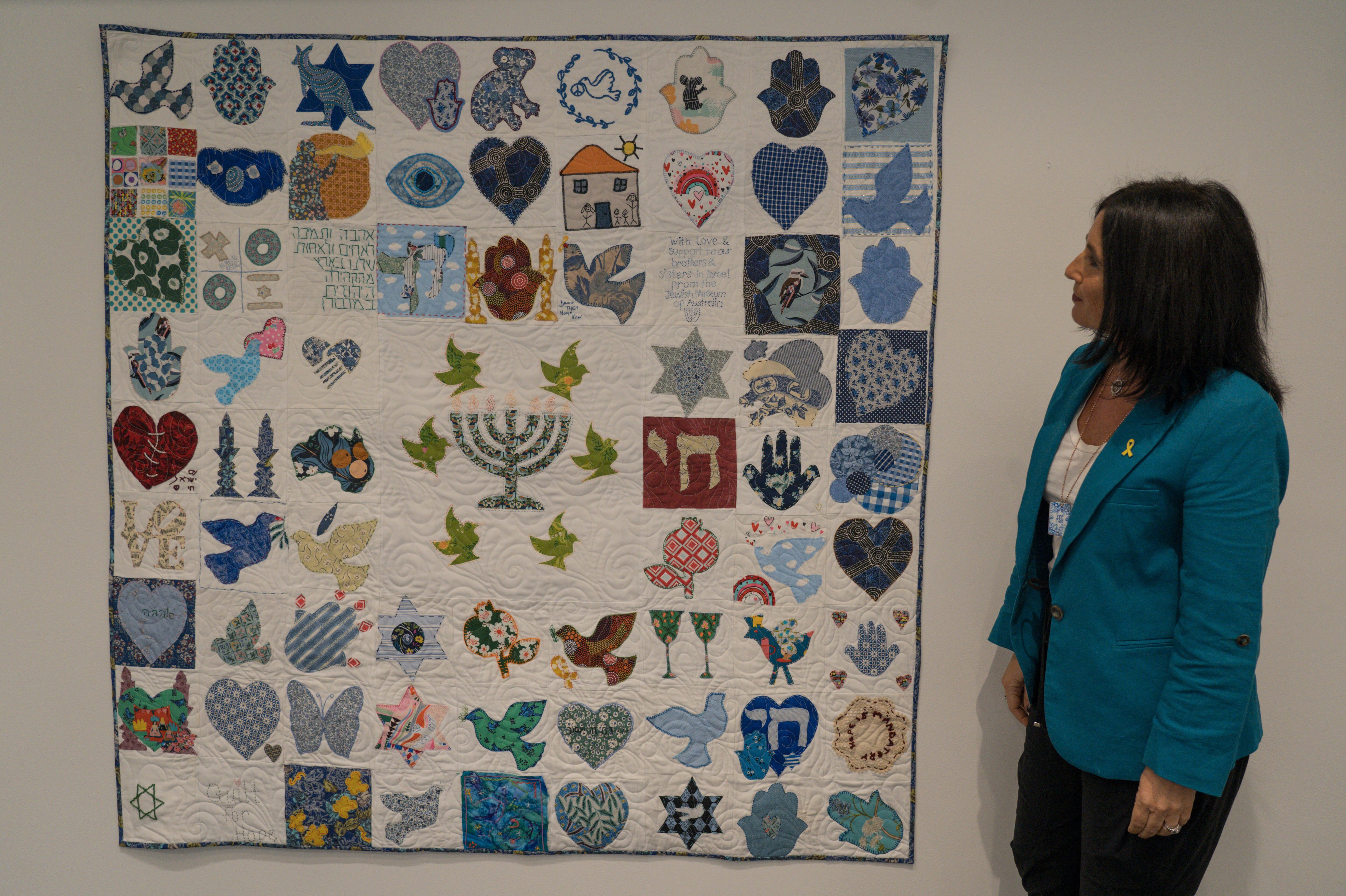 A woman in front of a quilt hung on a world