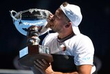 Dylan Alcott holds and kisses the Australian Open winner's trophy after the men's quad wheelchair singles final.
