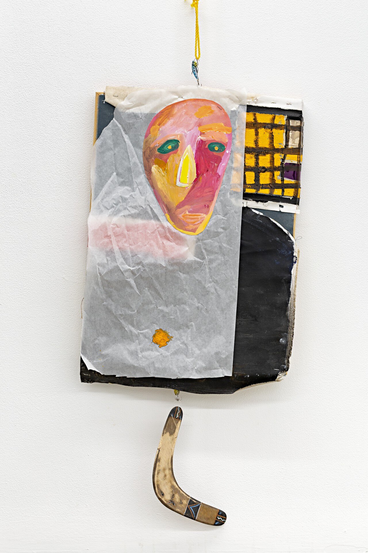 Abstract portrait painted on a layer of translucent paper attached to a painted canvas, with a boomerang hanging from the bottom