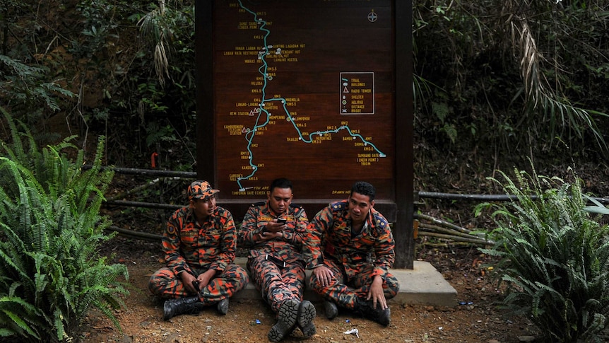 Malaysian quake rescue teams rest in front of trail sign