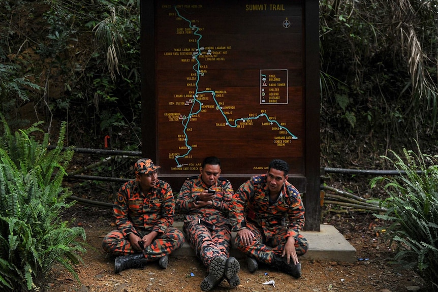 Malaysian quake rescue teams rest in front of trail sign