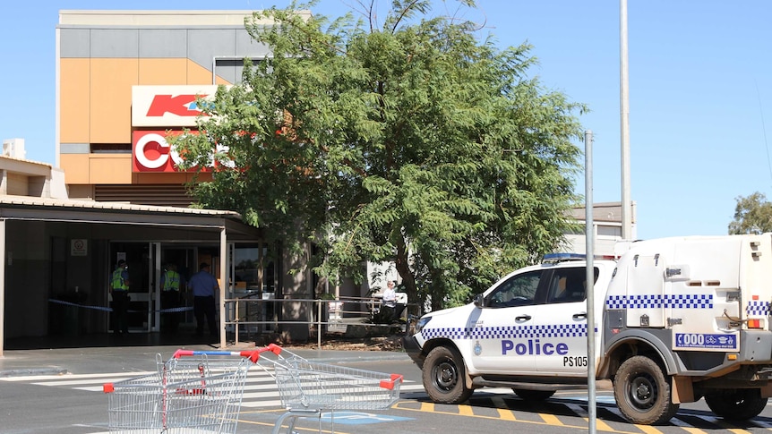 A police car parked outside a suburban shopping centre.