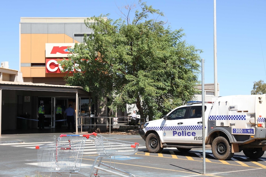 A police car parked outside a suburban shopping centre.