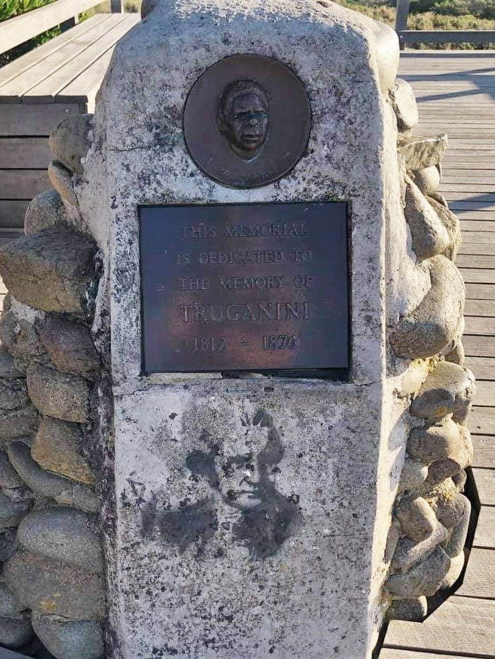 A memorial cairn with plaque of Truganini with Captain Cook stencil.