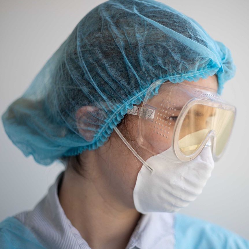 Female health worker in mask goggles and scrubs