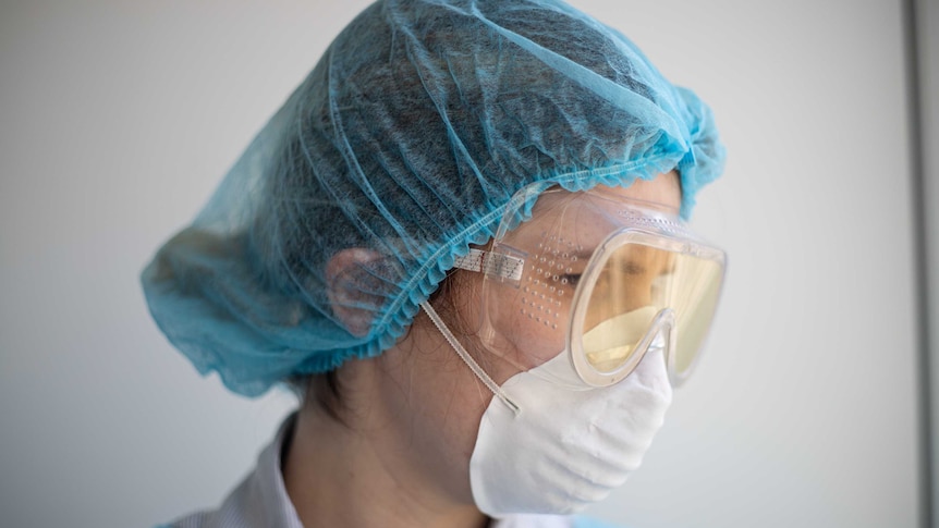 Female health worker in mask goggles and scrubs