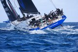The crew gather on the starboard side of a boat near the stern as it tilts into the waves during the Sydney to Hobart. 