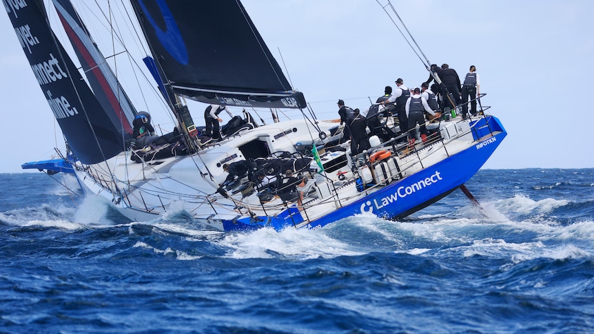 The crew gather on the starboard side of a boat near the stern as it tilts into the waves during the Sydney to Hobart. 