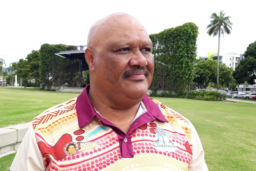 a man wearing a white and maroon polo standing in a park