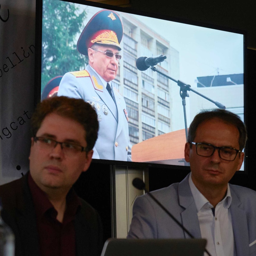 Eliot Higgins, founder of Bellingcat sits in front of screen projecting image of Russian Colonel General Delfin.