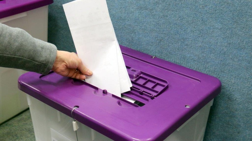 A voter puts a Senate paper into a ballot box