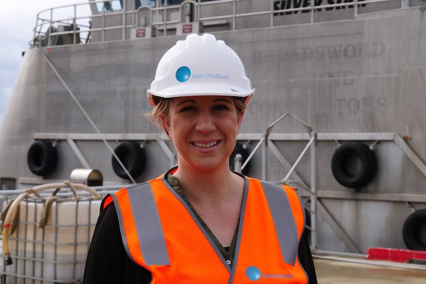A young woman wearing a hard hat, smiling at the camera.