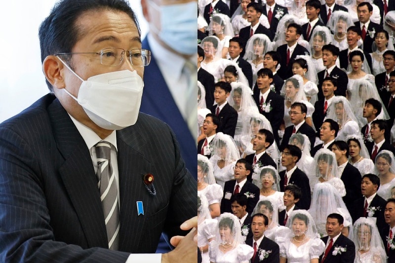 On left a Japanese man in suit and face mask sits at table, on right is a crowd wearing traditional bridal attire.