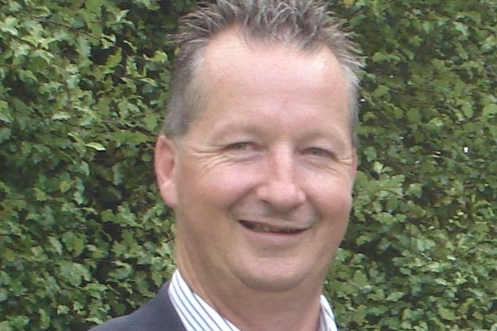 Peter Keeley, wearing a business shirt and jacket, poses for a formal photo.