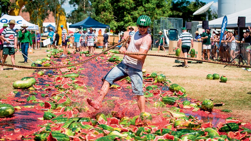 A man is pulled along with watermelons attached to his feet.