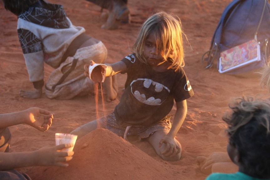 A child plays in the dirt at Uluru.
